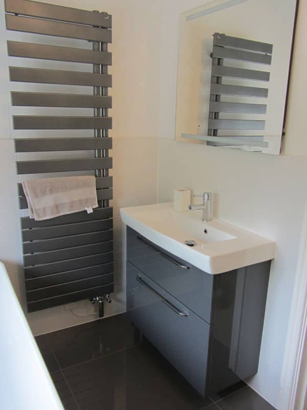 White long rectangle sink and grey cabinet underneath with a grey wall radiator